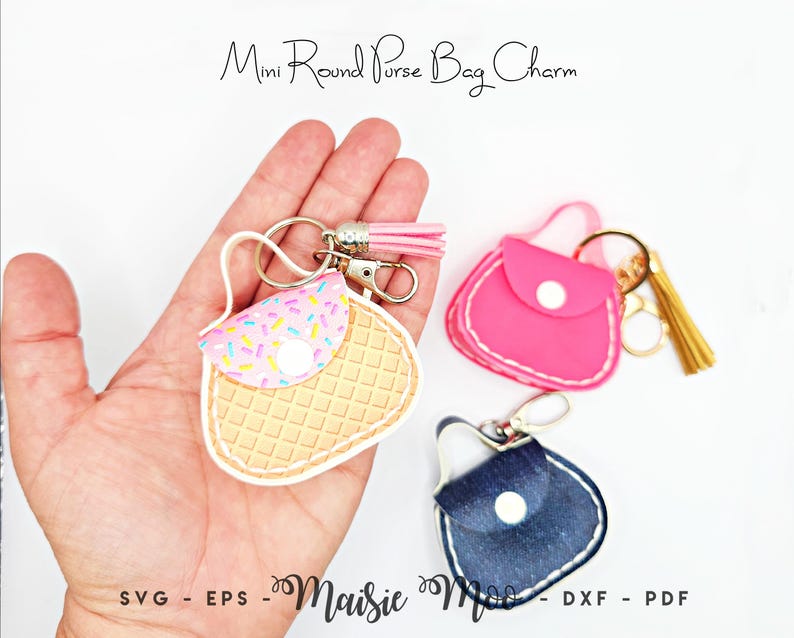 Peut inclure: Charm de sac en forme de mini sac &agrave; main, disponibles en rose, bleu jean et avec un motif gaufre. Le sac &agrave; main gaufre a un rabat avec des paillettes color&eacute;es. Chaque breloque comprend un porte-cl&eacute;s et un pompon. Le texte "Mini Round Purse Bag Charm" et "Maisie Moo" sont visibles.