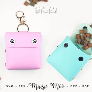 May include: A light pink square pet treat pouch with a metal lobster clasp and two white snap buttons featuring black paw prints. Beside it, an open light blue pet treat pouch contains brown kibble pieces, secured with black snap buttons.