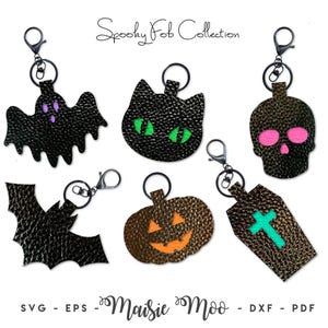 May include: A collection of six textured faux leather keychains featuring Halloween-themed shapes including a black ghost with purple eyes, a black cat head with green eyes, a skull with pink eyes, a black bat, a pumpkin, and a coffin with a teal cross.