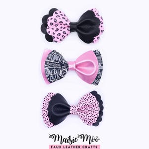 Puede incluir: Tres lazos decorativos dispuestos verticalmente. El lazo superior presenta un estampado de leopardo negro y rosa con bordes festoneados. El lazo central muestra un patrón escolar en blanco y negro con el texto School education. El lazo inferior es de lunares negros y rosas.