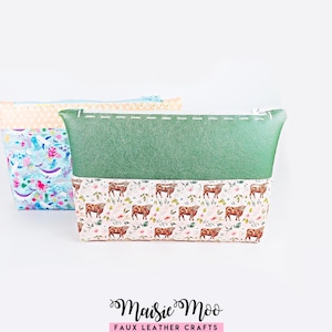 May include: Two zippered pouches. The front pouch features a dark green faux leather top section and a bottom section with a pattern of brown cows and pink flowers. The back pouch has a light orange polka dot top and a colourful aquatic animal print.
