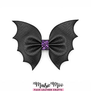 May include: A black faux leather hair bow shaped like bat wings with a textured surface. The center of the bow features a band of purple glitter. Below the bow, the text Maisie Moo FAUX LEATHER CRAFTS is printed in black and pink.