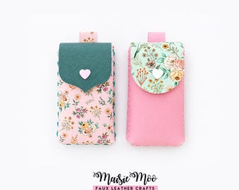 May include: Two rectangular pouches with top flaps. The left pouch has a pink floral body, a dark green flap, and a light pink heart button. The right pouch has a solid pink body, a light green floral flap, and a white heart button. Text reads Maisie Moo.