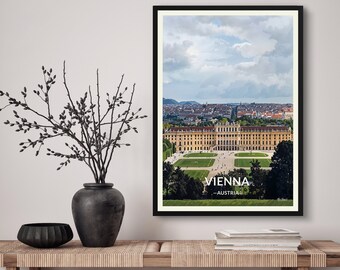 May include: A framed print of a scenic view of Vienna, Austria. The image features a large palace with a green lawn in front of it. The city skyline is visible in the background. The text "VIENNA - AUSTRIA -" is printed below the image.