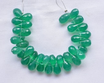 May include: A strand of green gemstone beads, each bead is faceted and shaped like a teardrop. The beads are strung on a silver wire.