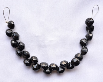 May include: A strand of black faceted gemstone beads strung on a silver wire with silver clasps at each end.