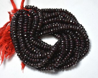 Puede incluir: Una hebra de cuentas de piedras preciosas facetadas de color rojo oscuro. Las cuentas son redondas y tienen un acabado liso y pulido. La hebra mide aproximadamente 40 cm de largo.