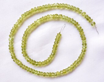 May include: A strand of light green gemstone beads, strung on a wire, with a faceted, slightly irregular shape.