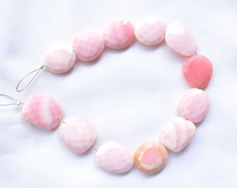 May include: A strand of pink opal beads, each bead is faceted and has a unique pattern. The beads are strung on a silver wire.