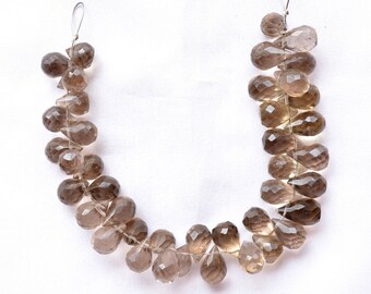May include: A strand of smoky quartz gemstone beads in a teardrop shape. The beads are faceted and strung on a clear thread.