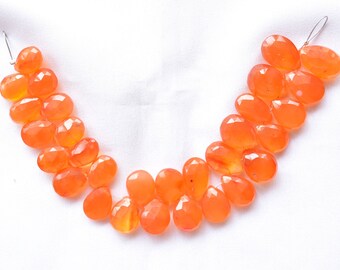 May include: A strand of orange carnelian gemstone beads, each bead is faceted and has a teardrop shape.