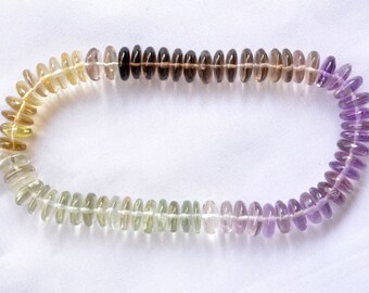 May include: A strand of gemstone beads in a gradient of colors, starting with light yellow and transitioning to purple. The beads are oval-shaped and have a smooth, polished finish.