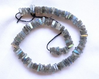 May include: A strand of gray labradorite gemstone beads, each bead is a rectangular shape with a slightly iridescent sheen.