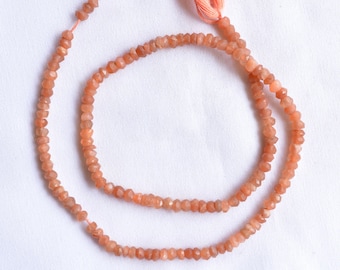 May include: A strand of orange sunstone beads with a faceted finish. The beads are strung on a thin cord with a tassel at the end.