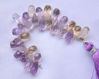 May include: A strand of faceted amethyst and citrine gemstone beads in a gradient of purple, pink, and brown. The beads are strung on a wire and have a tassel at the end.
