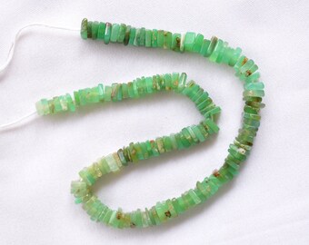 May include: A strand of small, flat, rectangular green chrysoprase beads strung on a thin white cord. The beads feature varying shades of translucent light to medium green with natural brown inclusions and a smooth, polished surface finish.
