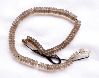 May include: A strand of smoky quartz beads, faceted and strung on a black thread. The beads are a light brown color and have a slightly translucent appearance.