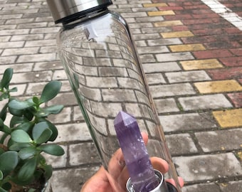 May include: A clear glass water bottle with a stainless steel lid and a purple amethyst crystal inside.