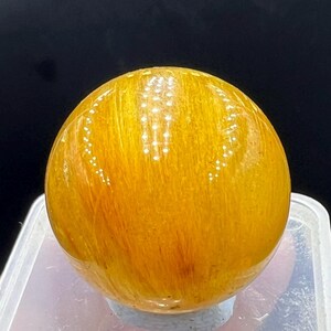 May include: A smooth, round, yellow sphere with a striated pattern. The sphere is made of a translucent material and has a glossy finish.