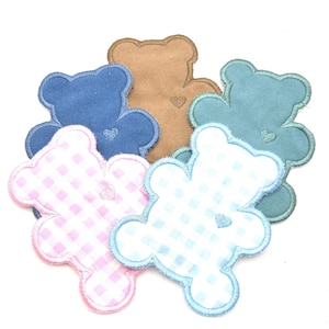 May include: A collection of five bear-shaped fabric patches featuring embroidered edges and a small heart detail on the chest. Two patches have a pink and blue gingham pattern, while the others are solid blue, tan, and teal fabric.
