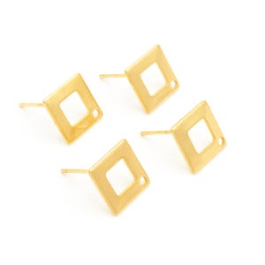 Könnte beinhalten: Vier goldfarbene quadratische Ohrstecker mit einem kleinen Loch in der Mitte jedes Quadrats. Die Ohrringe liegen auf einem weißen Hintergrund.