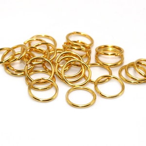 Pode incluir: Um monte de argolas de salto de metal dourado. As argolas são todas do mesmo tamanho e estão dispostas em um padrão aleatório.