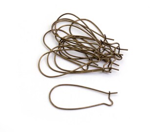 May include: A pile of gold-toned earring hooks, with one hook lying separately on a white background.