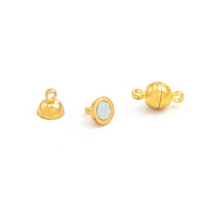 May include: Gold magnetic clasp for jewellery making. The clasp has two parts, a round ball with a loop and a flat disc with a post.