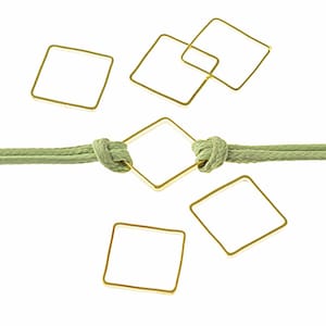 Może przedstawiać: Zielony sznurek z zawiązanym w środku złotym kwadratowym pierścieniem. Wokół sznurka rozrzuconych jest pięć dodatkowych złotych kwadratowych pierścieni.