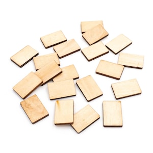 Può includere: Una collezione di piccoli blocchi di legno rettangolari sparsi su una superficie bianca. I blocchi sono marrone chiaro con venature del legno visibili e bordi marrone scuro. Questi rettangoli di legno non rifiniti sono adatti per lavori manuali e progetti fai-da-te.