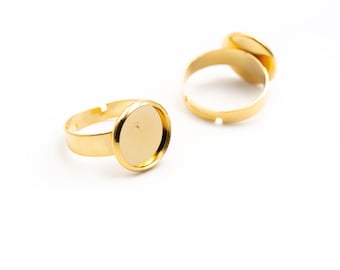 May include: Two gold-tone rings with round, empty settings for adding a decorative element. The rings are made of metal and have a smooth finish.