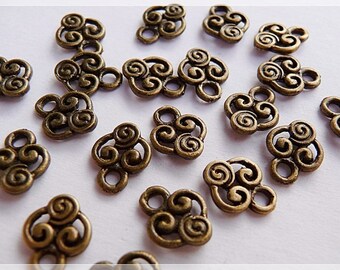Puede incluir: Un grupo de 18 abalorios de metal de color dorado antiguo con un diseño de espiral. Cada abalorio tiene un bucle en la parte superior para sujetarlo a joyas u otras manualidades.