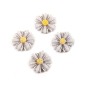 Puede incluir: Cuatro cabujones de resina de forma de margarita blanca con centros amarillos. Los cabujones tienen un diámetro de aproximadamente 2,5 cm.