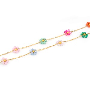 Könnte beinhalten: Zwei goldene Halsketten mit bunten Blumenanhängern aus Perlen in Rosa, Blau, Grün und Orange. Die Halsketten sind vor einem weißen Hintergrund abgebildet.