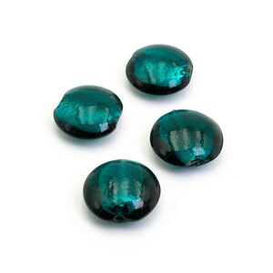 Könnte beinhalten: Vier teal-farbene, flache Glassteine mit runder Form. Das Glas hat eine glänzende, reflektierende Oberfläche und die Kanten sind dunkel. Die Steine sind auf einem weißen Hintergrund verstreut.