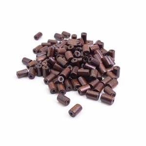 May include: A collection of small, dark brown wooden beads. Each bead is cylindrical with a hole through the centre. The beads are scattered on a white background, ideal for jewellery making or craft projects.