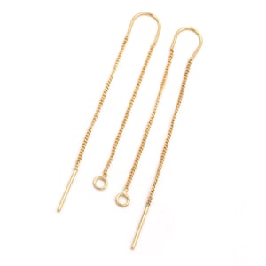 May include: A pair of gold chain earrings with a simple loop at the top and a straight, thin rod at the bottom.