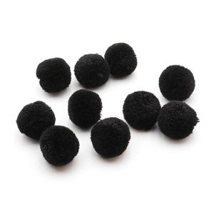 Op de afbeelding: Een verzameling van tien kleine, ronde, zwarte pompons gemaakt van zacht, pluizig garen. Elke pompon heeft een dichte, bolvormige vorm met een getextureerd, vezelig oppervlak, gerangschikt in een losse groep tegen een neutrale achtergrond.