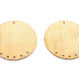 May include: Two round, gold-coloured metal discs with holes around the edges. The discs have a textured surface.