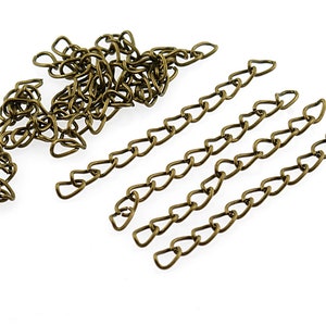 Könnte beinhalten: Nahaufnahme eines Stapels goldfarbener Metallkette. Die Kette besteht aus kleinen, miteinander verbundenen, herzförmigen Teilen. Es gibt auch fünf gerade Stücke der Kette, die in einer Reihe angeordnet sind.