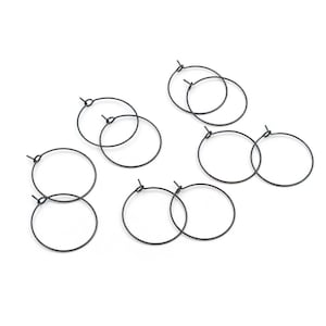 Peut inclure: Un ensemble de dix anneaux métalliques fins et circulaires avec une finition gris anthracite foncé. Chaque anneau présente un mécanisme de fermeture simple en fil de fer, disposé par paires, offrant un design uniforme pour la bijouterie.