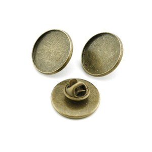Peut inclure: Trois supports ronds en métal doré antique pour épingles. Les supports sont conçus pour contenir un cabochon rond en verre.