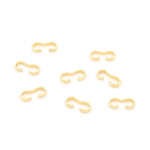 Può includere: Una collezione di otto connettori per gioielli dorati a forma di S. Ogni connettore ha una superficie strutturata e un design curvo, perfetto per la creazione di gioielli. I connettori sono sparsi su uno sfondo bianco.