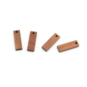 Puede incluir: Cuatro etiquetas rectangulares de madera con un agujero en la parte superior. Las etiquetas son de color marrón claro.