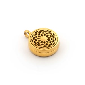 May include: A gold-coloured, round pendant with a floral filigree design on the top. The pendant has a small loop for a chain and a simple, elegant design. The pendant is likely made of metal and is set against a white background.