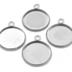 Könnte beinhalten: Vier silberfarbene Anhänger-Tabletts mit runder Form und einer Öse oben. Die Tabletts sind für die Aufnahme kleiner Gegenstände wie Harz, Glas oder anderer Materialien konzipiert.