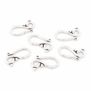 Op de afbeelding: Zes zilverkleurige haaksluitingen, ideaal voor het maken van sieraden. Elke sluiting heeft een gebogen haakontwerp met decoratieve balaccenten. De sluitingen zijn gerangschikt op een witte achtergrond, die hun details benadrukt.