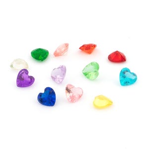 Könnte beinhalten: Eine Sammlung von zwölf herzförmigen, facettierten Edelsteinen in verschiedenen Farben, darunter Rot, Blau, Grün, Violett, Gelb, Rosa und Transparent. Jeder kleine Stein hat eine spitze Basis und eine flache Oberseite mit Facetten.