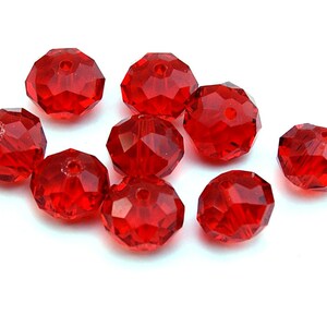 Puede incluir: Un conjunto de nueve cuentas redondas facetadas en un color rojo vibrante y translúcido. Cada cuenta presenta un orificio central para ensartar y una superficie de múltiples facetas que refleja la luz, creando un aspecto brillante y reluciente.