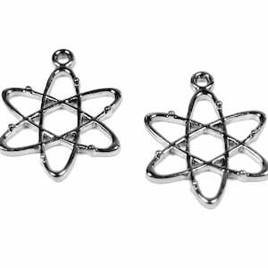 Könnte beinhalten: Zwei silberne Atom-Anhänger. Jeder Anhänger ist eine stilisierte Darstellung eines Atoms mit einem Kern und umlaufenden Elektronen.